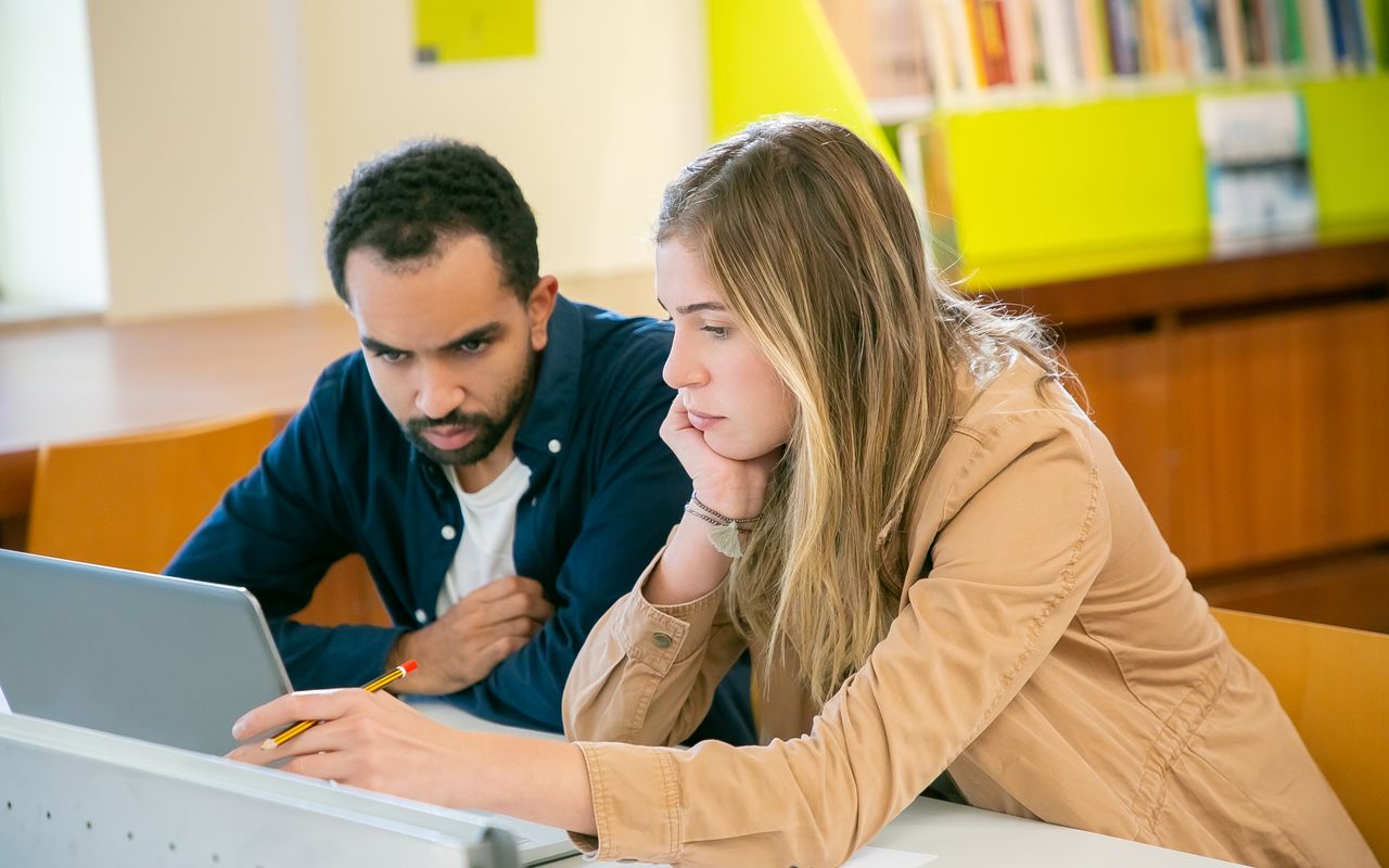 Estudantes trabalhando juntos com um computador em uma biblioteca
